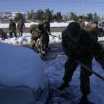 
              Army crews try to remove vehicles stranded in snow for three days along Attiki Odos tollway, linking Athens to the capital's international airport, Greece, Wednesday, Jan. 26, 2022. The efforts Wednesday came as authorities struggle to clear blocked roads and restore power to blacked out parts of the city. (AP Photo/Thanassis Stavrakis)
            