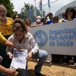 Demonstrators set fire to a COVID-19 vaccination card during a protest outside the Pan American Health Organization headquarters against COVID-19 vaccine passports and obligatory vaccines for COVID-19 for children, during a protest organized by supporters of Brazilian President Jair Bolsonaro in Brasilia, Brazil, Tuesday, Jan. 4, 2022. (AP Photo/Eraldo Peres)