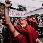 
              A Buddhist monk raises his clenched fist while marching during an anti-military government protest rally on Tuesday, Feb. 1, 2022, in Mandalay, Myanmar. The new U.N. special envoy for Myanmar says violence has intensified since the military took power a year ago and sparked a resistance movement in the country. (AP Photo)
            