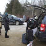 
              Migrants, right, remove their luggage from a taxi, in Champlain, N.Y., as they prepare to cross the Canadian border to arrive at a reception center for irregular borders crossers, less than 100 feet (about 30 meters) away, in Saint-Bernard-de-Lacolle, Quebec, in Canada, Wednesday Jan. 12, 2022. The refugees are crossing the U.S.-Canadian border where they are arrested by the Royal Canadian Police in Saint-Bernard-de-Lacolle, Quebec, and then allowed to make asylum claims and remain in Canada while those claims are processed. The process was halted for most cases after the 2020 outbreak of COVID-19, but the Canadian government changed its policy in November, allowing the process to continue. (AP Photo/Wilson Ring)
            