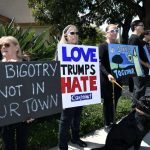 
              FILE - People gathering on a street corner hold signs in support of the victims of the Chabad of Poway synagogue shooting, Sunday, April 28, 2019, in Poway, Calif. A man opened fire the previous day inside the synagogue near San Diego as worshippers celebrated the last day of a major Jewish holiday. (AP Photo/Denis Poroy, File)
            