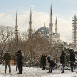 
              People walk in a snow-covered park with with Sultan Ahmed or Blue Mosque in the background at Istanbul, Tuesday, Jan. 25, 2022. Rescue crews in Istanbul and Athens on Tuesday cleared roads that had come to a standstill after a massive cold front and snowstorms hit much of Turkey and Greece, leaving countless people and vehicles in both cities stranded overnight in freezing conditions.(AP Photo/Emrah Gurel)
            