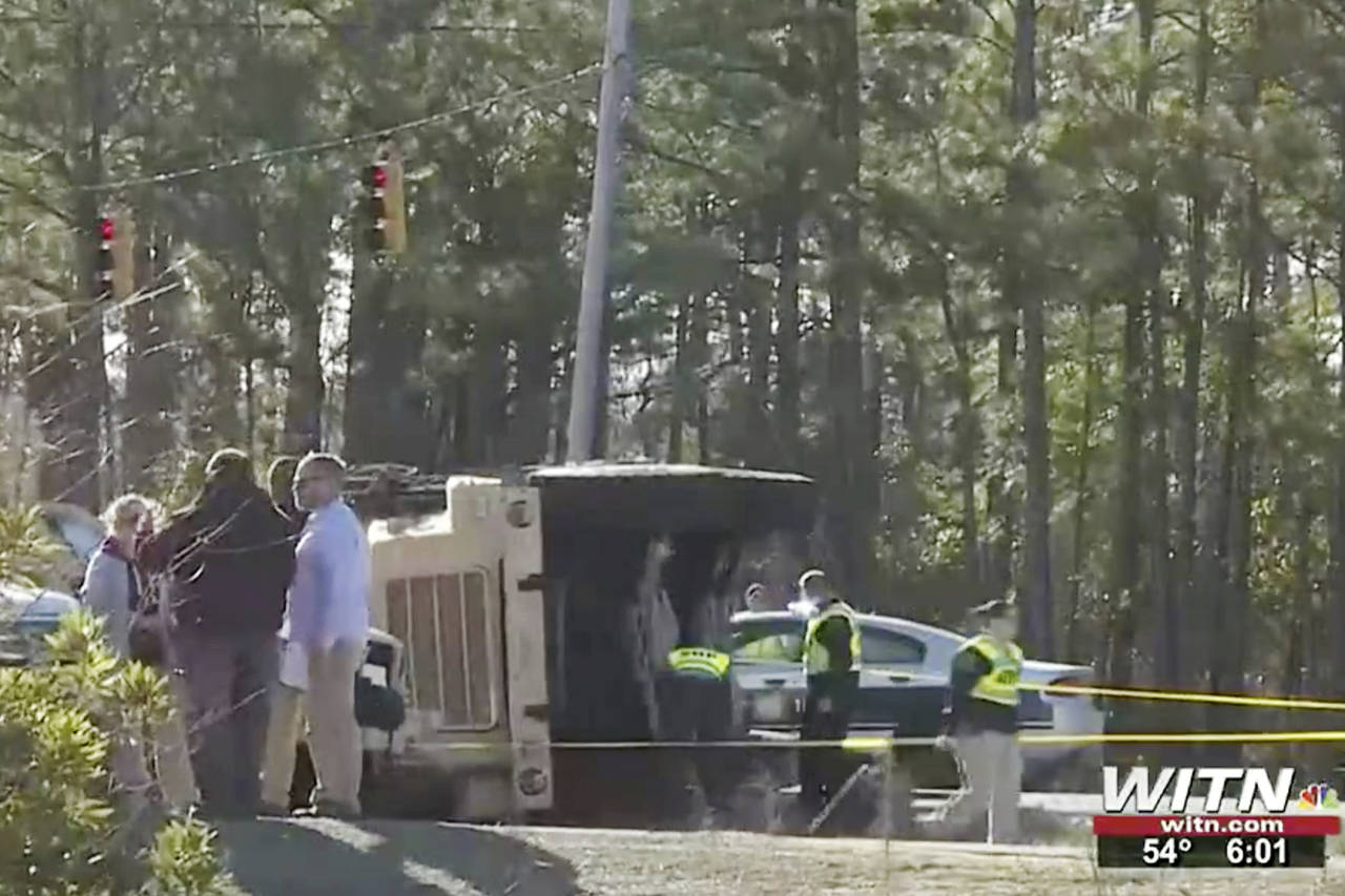 In this image taken from video, authorities work at the scene of a fatal crash after a military tru...