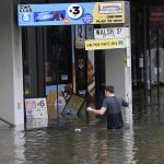 
              A man wades through flood waters in suburban Brisbane, Australia, Monday, Feb. 28, 2022. Heavy rain is bringing record flooding to some east coast areas and claimed seven lives while the flooding in Brisbane, a population of 2.6 million, and its surrounds is the worst since 2011 when the city was inundated by what was described as a once-in-a-century event. (Darren England/AAP Image via AP)
            