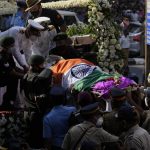 
              Defense forces and police carry the body of Lata Mangeshkar, outside her home in Mumbai, India, Sunday, Feb.6, 2022. The legendary Indian singer with a prolific, groundbreaking catalog and a voice recognized by a billion people in South Asia, died Sunday morning of multiple organ failure. She was 92. (AP Photo/Rafiq Maqbool)
            