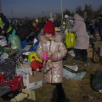 
              A Ukrainian refugee girl collects a toy from a pile of donated clothes at the Medyka border crossing, in Medyka, Poland, Saturday, Feb. 26, 2022. The U.N. refugee agency said Saturday that nearly 120,000 people have so far fled into neighboring countries and that number is going up fast. (AP Photo/Bernat Armangue)
            