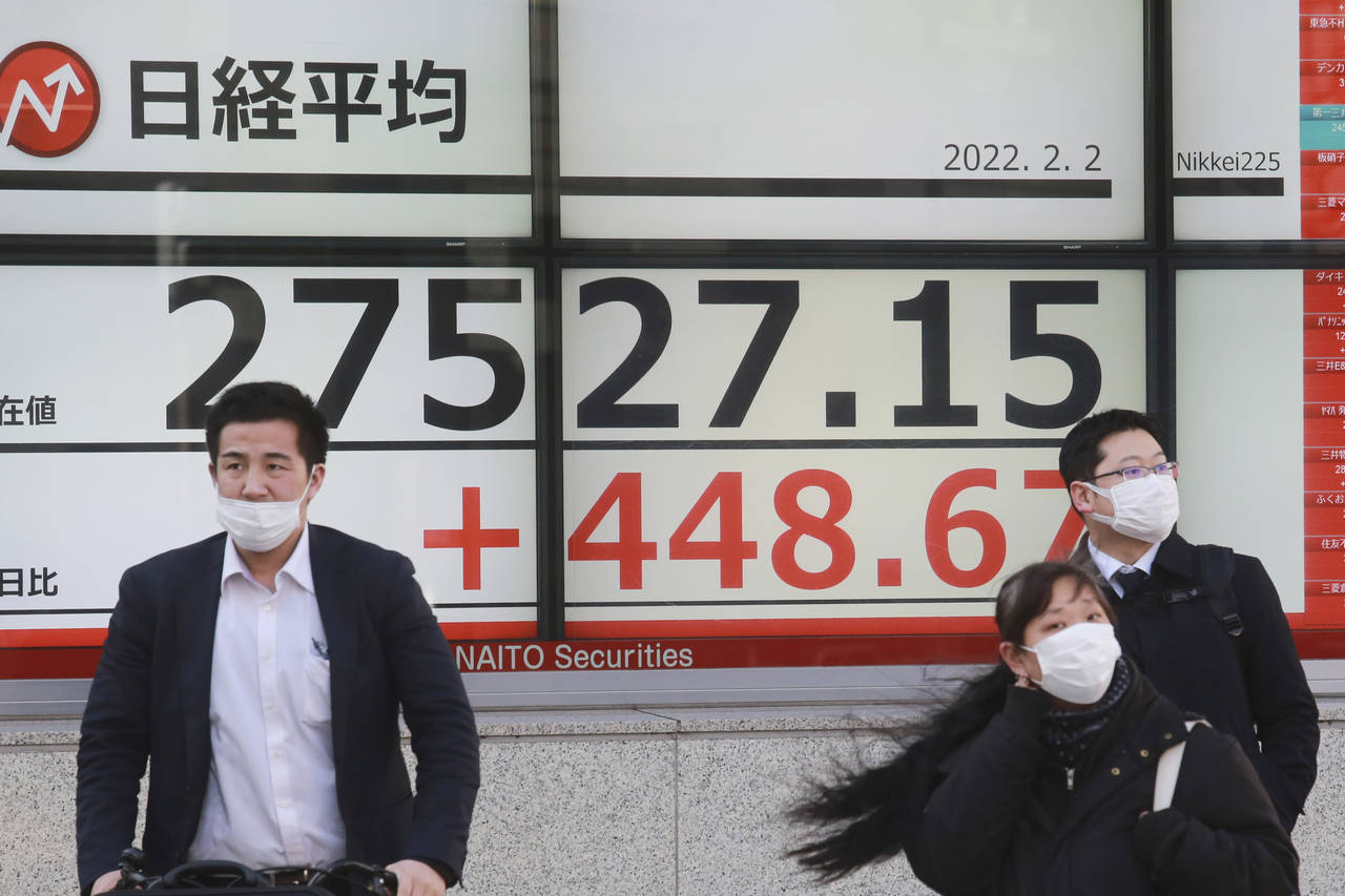 People walk by an electronic stock board of a securities firm in Tokyo, Wednesday, Feb. 2, 2022. St...