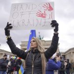 
              A banner reading "Hands off Ukraine" is held aloft during a demonstration against the war in Ukraine in front of the Brandenburg Gate in Berlin, Germany, Saturday, Feb. 26, 2022. (Joerg Carstensen/dpa via AP)
            