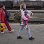 
              A woman carries a child while walking on a platform to board a Kyiv-bound train in Kostiantynivka, the Donetsk region, eastern Ukraine, Thursday, Feb. 24, 2022. Russia launched a wide-ranging attack on Ukraine on Thursday, hitting cities and bases with airstrikes or shelling, as civilians piled into trains and cars to flee. Ukraine's government said Russian tanks and troops rolled across the border in a “full-scale war” that could rewrite the geopolitical order and whose fallout already reverberated around the world. (AP Photo/Vadim Ghirda)
            
