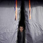 
              A child that fled the conflict from neighboring Ukraine with his family sits in a tent at the Romanian-Ukrainian border, in Siret, Romania, Sunday, Feb. 27, 2022. Since Russia launched its offensive on Ukraine, more than 200,000 people have been forced to flee the country to bordering nations like Romania, Poland, Hungary, Moldova, and the Czech Republic — in what the U.N. refugee agency, UNHCR, said will have "devastating humanitarian consequences" on civilians. (AP Photo/Andreea Alexandru)
            