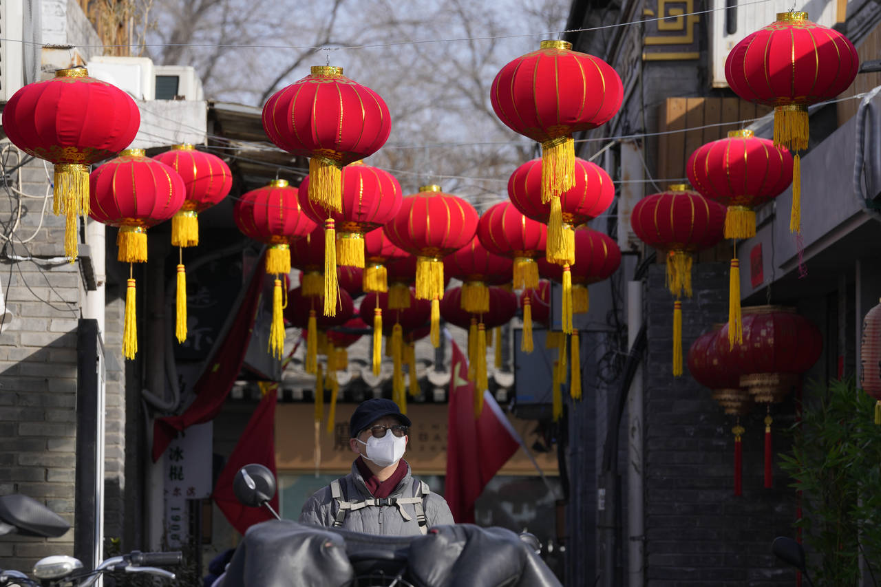 A resident wearing a face mask walks under red lanterns setup for the Lunar New Year holidays in Be...