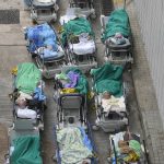 
              Patients lie on hospital beds as they wait at a temporary holding area outside Caritas Medical Centre in Hong Kong Wednesday, Feb.16, 2022. There was visible evidence that Hong Kong hospitals were becoming overwhelmed by the latest COVID surge, with patients on stretchers and in tents being seen to by medical personnel on Wednesday outside the Caritas hospital. (AP Photo Vincent Yu)
            
