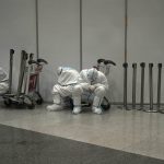 
              Olympic workers in protective clothing rest after they helped travelers at the Beijing Capital International Airport after the 2022 Winter Olympics, Monday, Feb. 21, 2022, in Beijing, China. (AP Photo/Alessandra Tarantino)
            