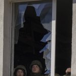 
              Ukrainian soldiers look out from a broken window inside a military facility, after an explosion in Kyiv, Ukraine, Saturday, Feb. 26, 2022. Russian troops stormed toward Ukraine's capital Saturday, and street fighting broke out as city officials urged residents to take shelter. (AP Photo/Emilio Morenatti)
            