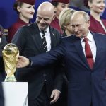 
              FILE - Russian President Vladimir Putin touches the World Cup trophy as FIFA President Gianni Infantino stands beside him, at the end of the final match between France and Croatia at the 2018 soccer World Cup in the Luzhniki Stadium in Moscow, Russia, Sunday, July 15, 2018. In a sweeping move to isolate and condemn Russia after invading Ukraine, the International Olympic Committee urged sports bodies on Monday to exclude the country's athletes and officials from international events. The decision opened the way for FIFA, the governing body of soccer, to exclude Russia from a World Cup qualifying playoff match on March 24. Poland has refused to play the scheduled game against Russia.(AP Photo/Petr David Josek, File)
            