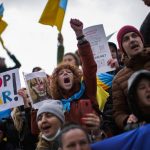 
              Pro-Ukrainian people shout slogans as they hold up banners and wave Ukrainian flags during a protest against Russia's invasion of Ukraine, in Istanbul, Turkey, Monday, Feb. 28, 2022. Explosions and gunfire that have disrupted life since the invasion began last week appeared to subside around Kyiv overnight, as Ukrainian and Russian delegations met Monday on Ukraine's border with Belarus. (AP Photo/Francisco Seco)
            