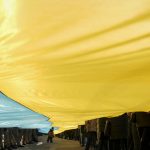 
              A child walks under a large Ukrainian flag carried by people marking a "day of unity" in Sievierodonetsk, the Luhansk region, eastern Ukraine, Wednesday, Feb. 16, 2022. Russian President Vladimir Putin said that he welcomed a security dialogue with the West, and his military reported pulling back some of its troops near Ukraine, while U.S. President Joe Biden said the U.S. had not verified Russia's claim and that an invasion was still a distinct possibility. (AP Photo/Vadim Ghirda)
            