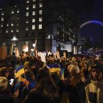 
              Demonstrators hold placards and Ukraine flags attend a protest outside Downing Street, with the London Eye is lit up in the colours of the Ukraine flag, in London, Friday, Feb. 25, 2022. Russia has launched a full-scale invasion of Ukraine, unleashing airstrikes on cities and military bases and sending troops and tanks from multiple directions in a move that could rewrite the world's geopolitical landscape. (AP Photo/Alberto Pezzali)
            