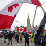 A person waves a Canadian flag in front of Parliament Hill during a protest against COVID-19 measures in Ottawa, Friday, Feb. 11, 2022. (Justin Tang/The Canadian Press via AP)