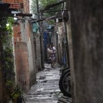 
              A woman, carrying a child, walks through an alley in “Puerta 8” in San Martín, a suburb north of of Buenos Aires, Argentina, Thursday, Feb. 3, 2022. According to local authorities, 20 people have died and dozens seriously sickened after consuming adulterated cocaine. Police said Thursday that the cocaine was sold in the “Puerta 8” neighborhood. (AP Photo/Rodrigo Abd)
            