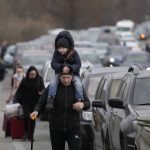 
              Ukrainian refugees walk along vehicles lining-up to cross the border from Ukraine into Moldova, at Mayaky-Udobne crossing border point near Mayaky-Udobne, Ukraine, Saturday, Feb. 26, 2022. The U.N. refugee agency says nearly 120,000 people have so far fled Ukraine into neighboring countries in the wake of the Russian invasion. The number was going up fast as Ukrainians grabbed their belongings and rushed to escape from a deadly Russian onslaught. (AP Photo/Sergei Grits)
            