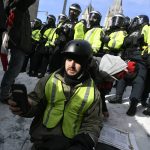 
              A man sits on the ground as police move in to clear protesters from downtown Ottawa near Parliament Hill on Saturday, Feb. 19, 2022.  Police resumed pushing back protesters on Saturday after arresting more than 100 and towing away vehicles in Canada’s besieged capital, and scores of trucks left under the pressure, raising authorities’ hopes for an end to the three-week protest against the country’s COVID-19 restrictions.  (Justin Tang /The Canadian Press via AP)
            