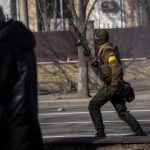 
              A Ukrainian soldier runs holding his weapon outside a military facility, in Kyiv, Ukraine, Saturday, Feb. 26, 2022. Russian troops stormed toward Ukraine's capital Saturday, and street fighting broke out as city officials urged residents to take shelter. (AP Photo/Emilio Morenatti)
            