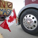 
              The Canadian flag is reflected in a wheel hub as anti-COVID-19 vaccine mandate demonstrators gather as a truck convoy blocks the highway at the busy U.S. border crossing in Coutts, Alberta, Canada, Monday, Jan. 31, 2022.   Thousands of antivaccine protesters descended on Canada’s capital of Ottawa in frigid temperatures to protest vaccine mandates, masks and restrictions over the weekend and some remain, blocking traffic around Parliament Hill in what has been the biggest pandemic protest in the country to date. (Jeff McIntosh/The Canadian Press via AP)
            