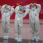 
              Olympic workers in protective clothing pose for a picture at the Beijing Capital International Airport after the 2022 Winter Olympics, Monday, Feb. 21, 2022, in Beijing, China. (AP Photo/Frank Augstein)
            
