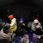 
              Refugees who fled the conflict from neighboring Ukraine sit in a waiting tent at the Romanian-Ukrainian border, in Siret, Romania, Saturday, Feb. 26, 2022. Romania, which shares around 600 kilometres (372 miles) of borders with Ukraine to the north, is seeing an influx of refugees from the country as many flee Russia's attacks. (AP Photo/Andreea Alexandru)
            
