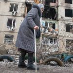 
              A woman walks past an apartment building hit by shelling in Kharkiv, Ukraine, Tuesday, March 8, 2022. (AP Photo/Andrew Marienko)
            