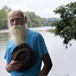 
              FILE — David Lidstone, 81, known to locals as "River Dave," stands for a photograph near the Merrimack River, Tuesday, Aug. 10, 2021, in Boscawen, N.H. A warrant has been issued for the arrest of the former hermit in New Hampshire who is charged with trespassing on the wooded property he made his home for 27 years after he didn't show up for his arraignment. A prosecutor said Monday, March 7, 2022, the state of New Hampshire has had no contact with 81-year-old David Lidstone on the misdemeanor charge. (AP Photo/Steven Senne, File)
            