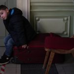 
              A young boy that fled the war in Ukraine sits in a suitcase at the Przemysl train station, southeastern Poland, on Saturday, March 12, 2022. Russian troops are pressing their offensive across Ukraine, pounding populated areas with artillery and airstrikes and deploying siege tactics honed in Syria and Chechnya — where opposing cities were reduced to rubble. (AP Photo/Daniel Cole)
            