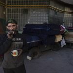 
              Worker Ruslan Trishchuk, 40, smokes a cigarette while taking a break outside the crematorium of Baikave cemetery in Kyiv, Ukraine, Monday, March 21, 2022. (AP Photo/Rodrigo Abd)
            