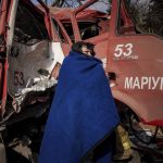 
              A woman covers herself with a blanket near a damaged fire truck after shelling in Mariupol, Ukraine, Thursday, March 10, 2022. (AP Photo/Evgeniy Maloletka)
            