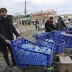 
              Local residents carry water from the food warehouse, on the territory which is under the Government of the Donetsk People's Republic control, on the outskirts of Mariupol, Ukraine, Friday, March 18, 2022. (AP Photo/Alexei Alexandrov)
            