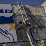 
              A worker sets up a billboard with the colors of Ukraine flag in Novoiavorisk, near Lviv, Western Ukraine, Friday, March 18, 2022. Ukrainian printing company Propet print has been installing patriotic-themed billboards in Lviv area since the start of the war. (AP Photo/Bernat Armangue)
            