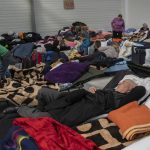 
              A man who fled Ukraine sleeps at a refugee center in Korczowa, Poland, on Sunday, March 13, 2022. Now in its third week, the war has forced more than 2.5 million people to flee Ukraine. (AP Photo/Petros Giannakouris)
            