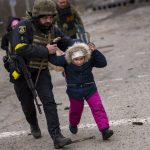 
              A Ukrainian police officer runs while holding a child as the artillery echoes nearby, while fleeing Irpin on the outskirts of Kyiv, Ukraine, Monday, March 7, 2022. Russia announced yet another cease-fire and a handful of humanitarian corridors to allow civilians to flee Ukraine. Previous such measures have fallen apart and Moscow's armed forces continued to pummel some Ukrainian cities with rockets Monday. (AP Photo/Emilio Morenatti)
            