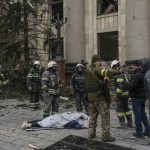 
              Ukrainian emergency service personnel and servicemen stand around a body of a victim following shelling of the City Hall building in Kharkiv, Ukraine, Tuesday, March 1, 2022. Russia on Tuesday stepped up shelling of Kharkiv, Ukraine's second-largest city, pounding civilian targets there. Casualties mounted and reports emerged that more than 70 Ukrainian soldiers were killed after Russian artillery recently hit a military base in Okhtyrka, a city between Kharkiv and Kyiv, the capital. (AP Photo/Pavel Dorogoy)
            