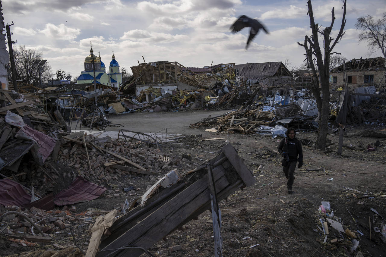 A journalist walks amid the destruction after a Russian attack in Byshiv, in the outskirts of Kyiv,...