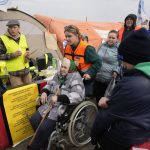 
              An aide helps a woman in a wheelchair as she waits in a queue after fleeing the war from neighbouring Ukraine at the border crossing in Medyka, southeastern Poland, on Tuesday, March 29, 2022. The daily number of people fleeing Ukraine has fallen in recent days but border guards, aid agencies and refugees say Russia's unpredictable war offers few signs whether it's just a temporary lull or a permanent drop-off. (AP Photo/Sergei Grits)
            
