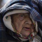 
              Sofia Boiko, 90 years old, arrives at the Ukrainian Red Cross center in Mykolaiv, southern Ukraine, on Monday, March 28, 2022. Boiko who is traveling alone and other people evacuated from regions that have been attacked by the Russian army in Mykolaiv district. The more than month-old war has killed thousands and driven more than 10 million Ukrainians from their homes — including almost 4 million from their country. (AP Photo/Petros Giannakouris)
            