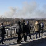
              Pedestrians walk over an overpass as a cloud of smoke raises after an explosion in Lviv, Western Ukraine, Friday, March 18, 2022. The mayor of Lviv says missiles struck near the city's airport early Friday. (AP Photo/Bernat Armangue)
            