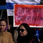 
              Protesters take part in a protest against Russia's invasion of Ukraine, in southern port city of Limassol, Cyprus, Sunday, March 13, 2022. Dozens of Russian nationals joined Ukrainians in the coastal resort town of Limassol Sunday to protest the war in Ukraine, chanting slogans like "Stop the war, stop Putin" and waving blue and white flags they said where the Russian national flag without the red stripe that represented "blood and violence." (AP Photo/Petros Karadjias)
            