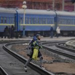 
              A woman carries a baby over the tracks trying to board a Lviv bound train, in Kyiv, Ukraine, Thursday, March 3, 2022. Ukrainian President Volodymyr Zelenskyy's office says a second round of talks with Russia aimed at stopping the fighting that has sent more than 1 million people fleeing over Ukraine's borders, has begun in neighboring Belarus, but the two sides appeared to have little common ground. (AP Photo/Vadim Ghirda)
            