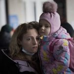 
              A woman holds her daughter as they try to get on a train at the Kyiv station, Ukraine, Friday, March 4. 2022. Ukrainian men have to stay to fight in the war while women and children are leaving the country to seek refuge in a neighboring country. (AP Photo/Emilio Morenatti)
            