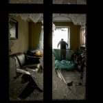 
              Slava Chikov covers the shattered window of his living room with a plastic sheet in a building damaged by a bombing the previous day in Kyiv, Ukraine, Monday, March 21, 2022. (AP Photo/Vadim Ghirda)
            