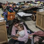 
              Kate who fled Ukraine reads a story to her 16 month daughter Dianna in a refugee center in Korczowa, Poland, on Sunday, March 13, 2022. Now in its third week, the war has forced more than 2.5 million people to flee Ukraine. (AP Photo/Petros Giannakouris)
            