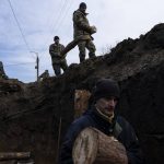 
              Soldiers carry wooden logs while building a trench, in Lityn, Ukraine, Wednesday, March 16, 2022. (AP Photo/Rodrigo Abd)
            